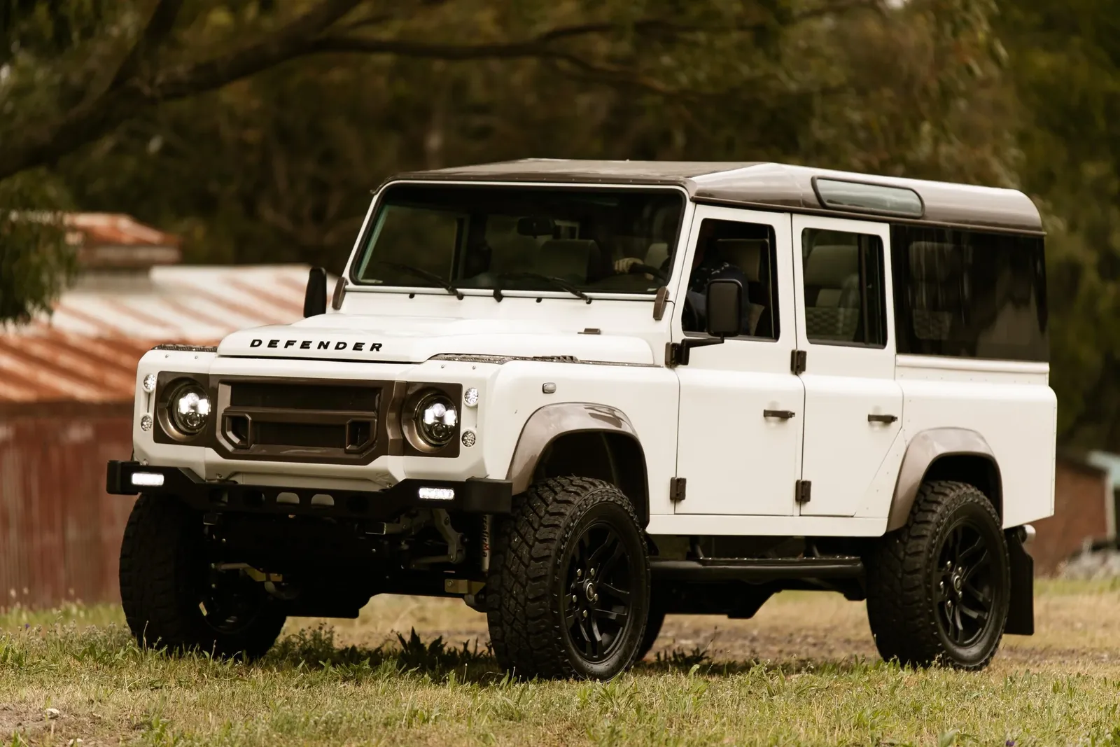 White Land Rover Defender 110 on grass, front three-quarter view